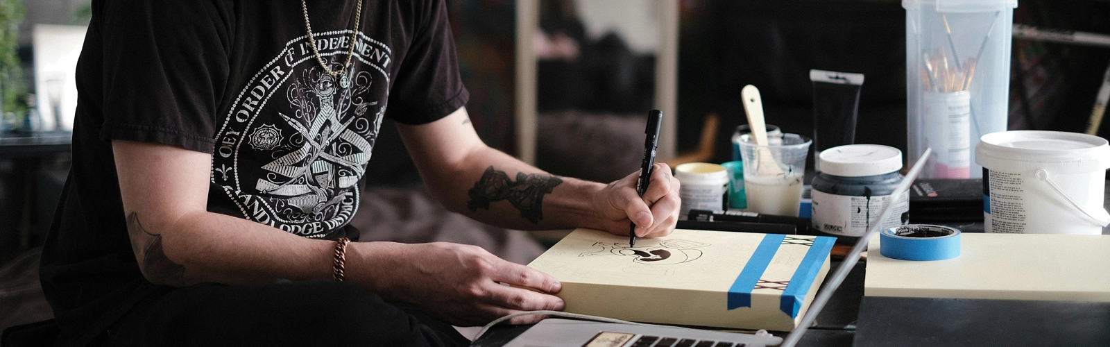 En man sitter vid ett skrivbord och målar på ett papper.