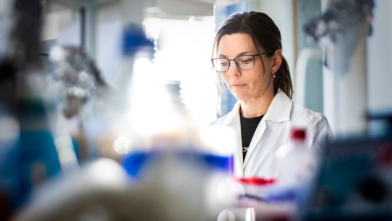 A woman in a lab coat in focus, in the foreground blurred instruments.