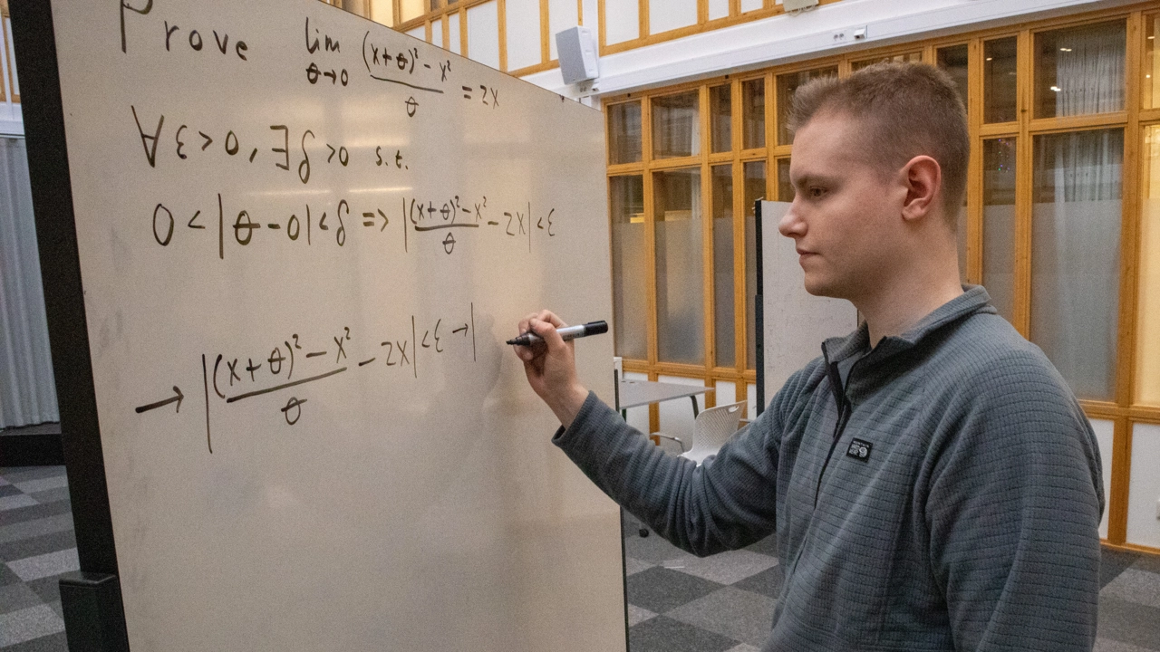 Bild på Christian Ekholm som står vid whiteboardtavla och läser matematiktal