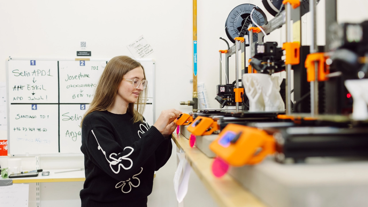 En ung kvinnlig student vid en 3D-skrivare.