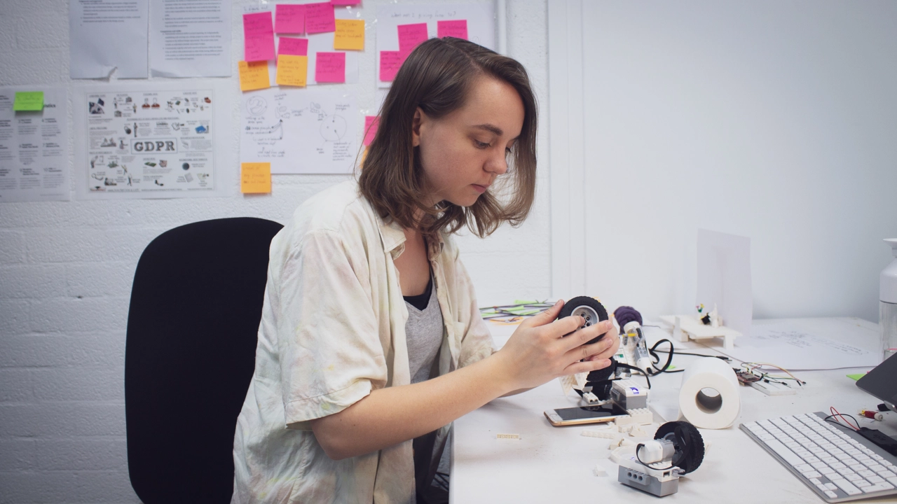 Bild på Ilse Pouwels i arbete med sitt examensprojekt, sitter vid arbetsbord