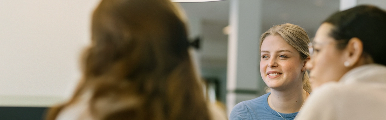 En kvinna i blå tröja ler och tittar åt ett annat håll.