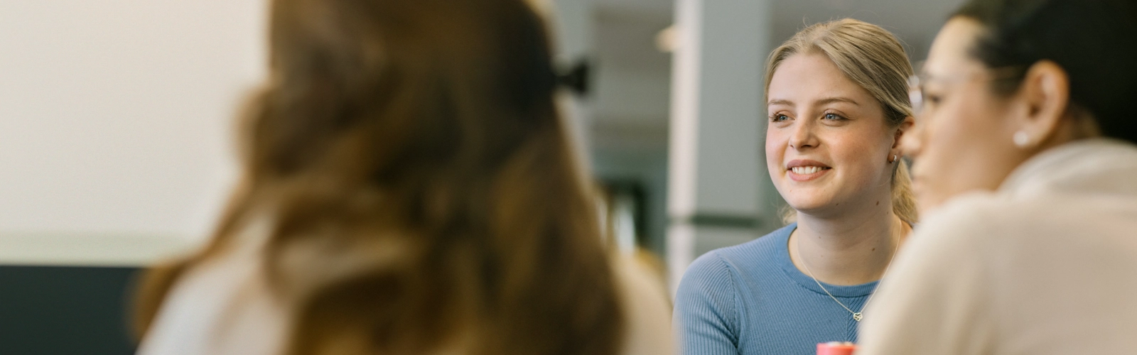 En kvinna i blå tröja ler och tittar åt ett annat håll.