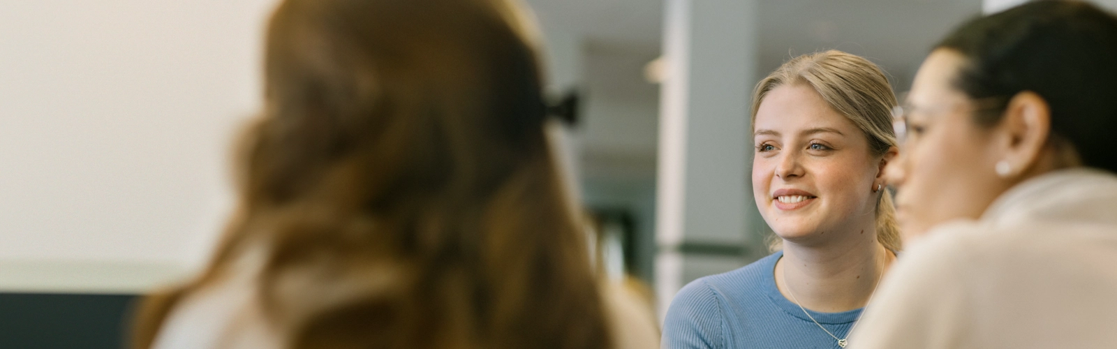 En kvinna i blå tröja ler och tittar åt ett annat håll.