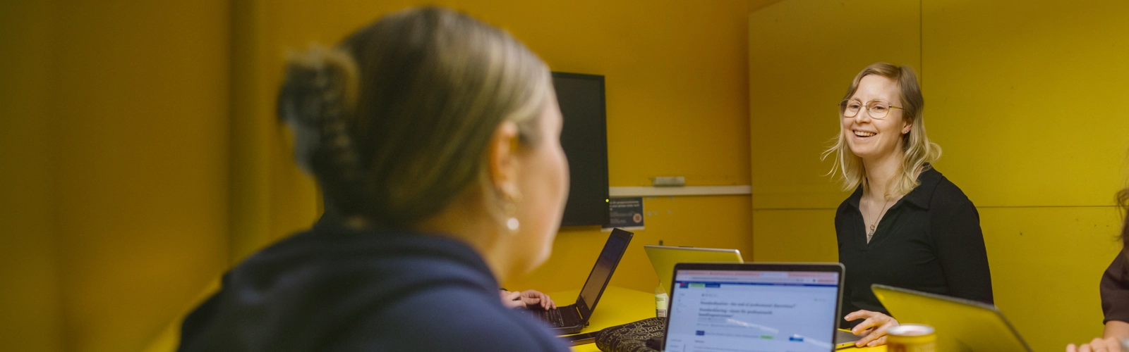 Umeå Universitet, Humanisthuset. Studenter pluggar i ett gult grupprum.