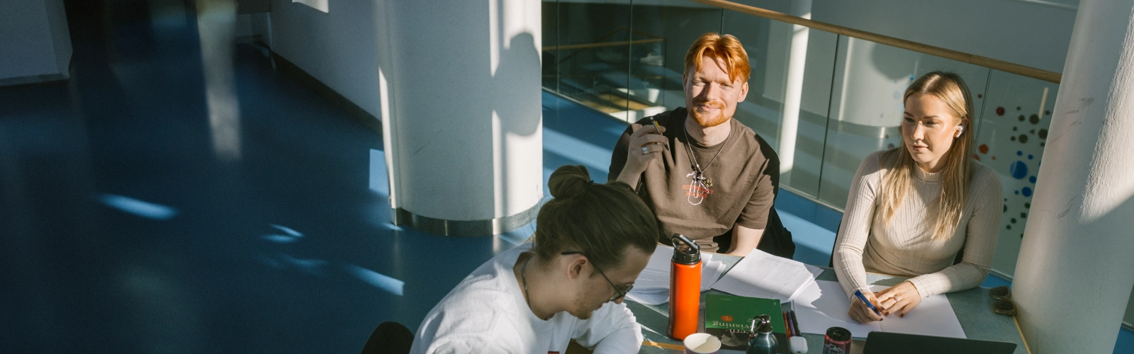 Tre personer sitter vid ett bord och pluggar.
