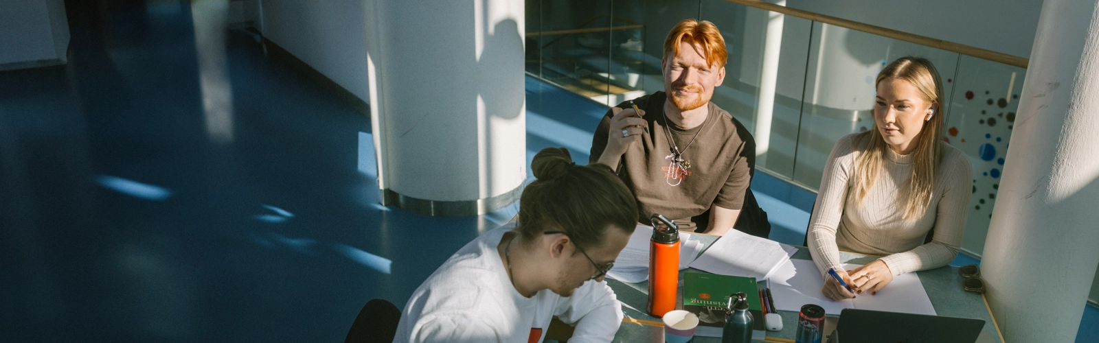 Tre personer sitter vid ett bord och pluggar.