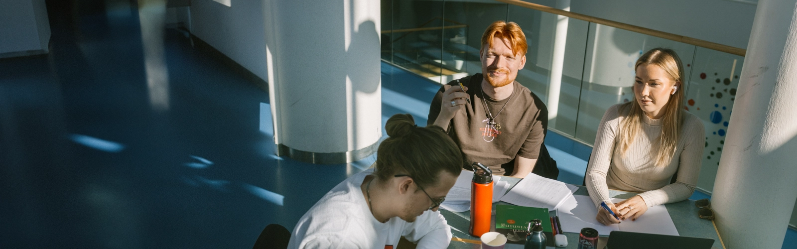 Tre personer sitter vid ett bord och pluggar.