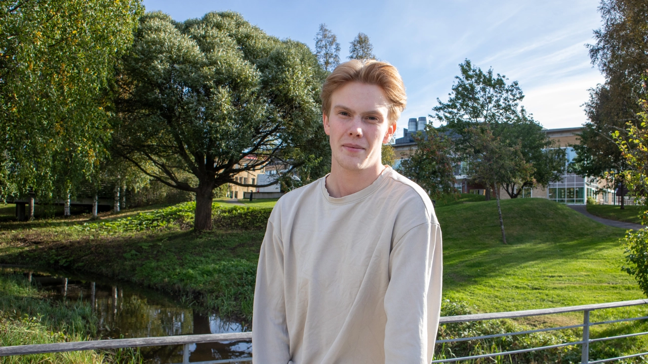 Porträttfoto på Edwin Gustafsson, i bakgrunden grönområde på campus