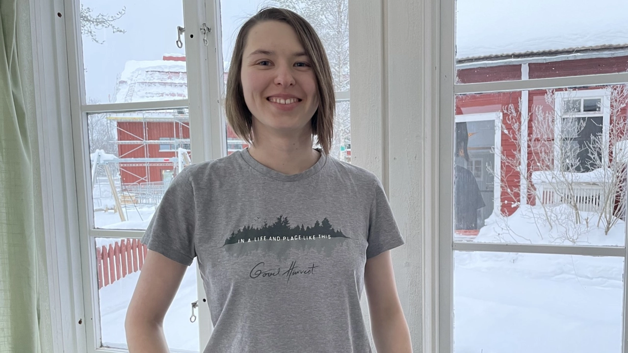 Bild på Emilia Harr stående med ett fönster i bakgrunden