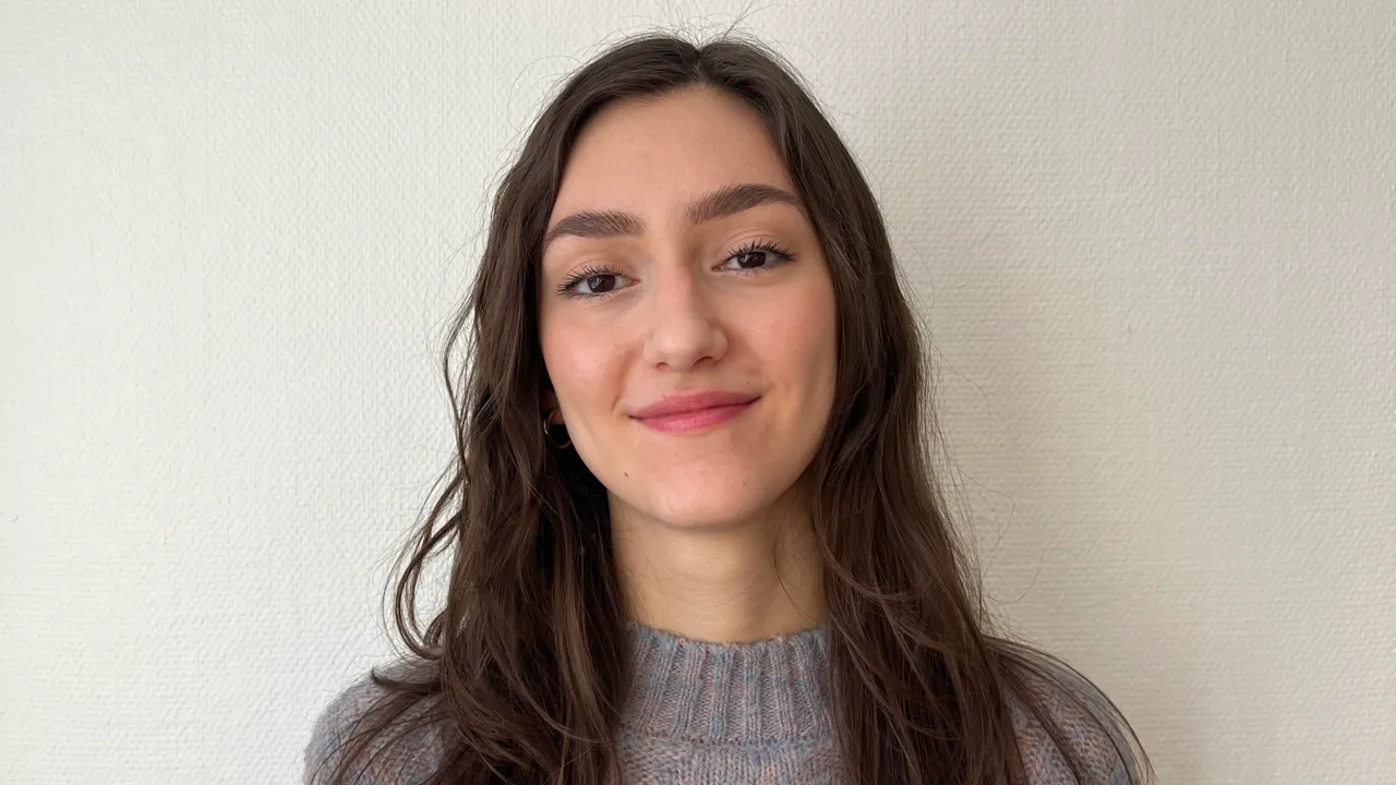 Emma Biondani, arkitektstudent, stående i halvfigur med vit vägg i bakgrunden