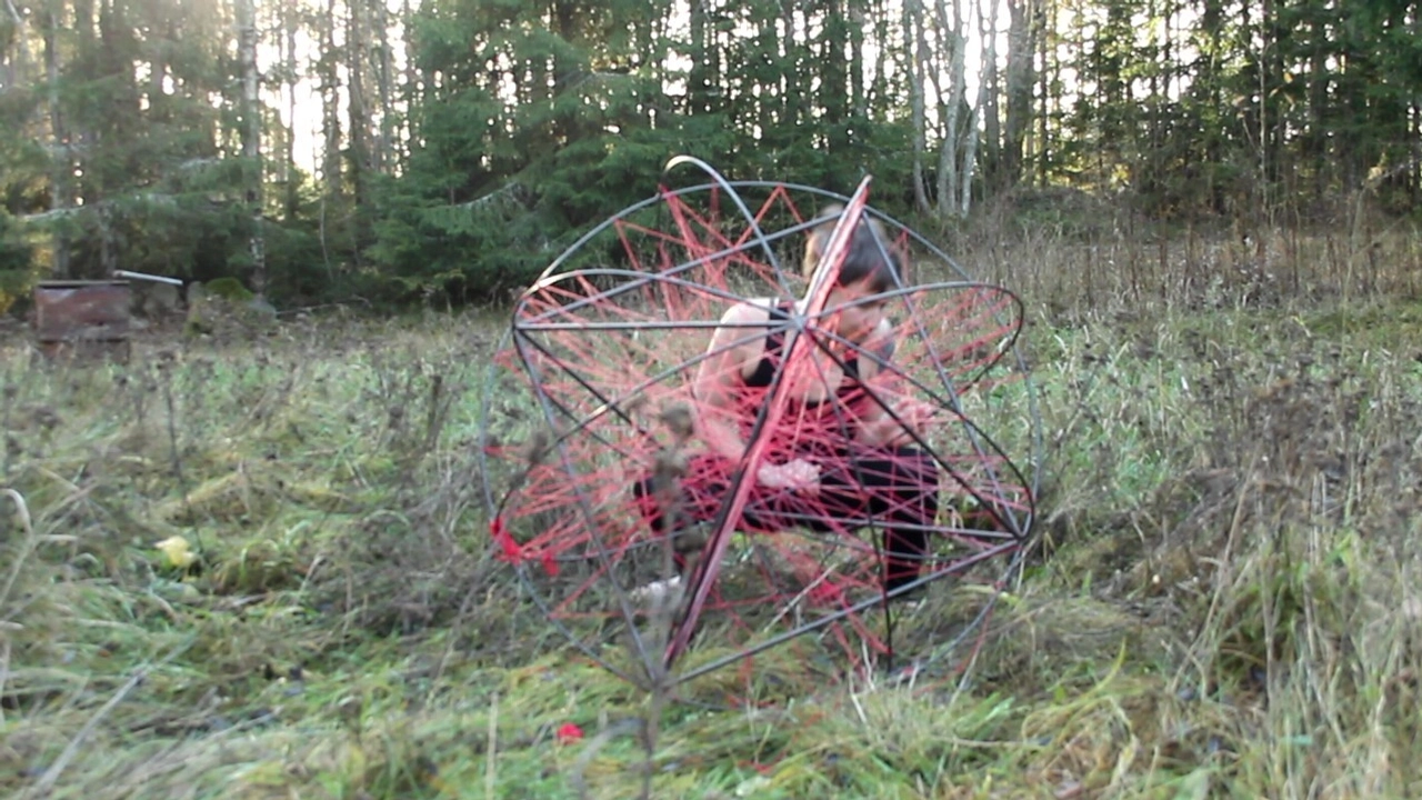 Person på äng snurrar ett klot av stål och garn