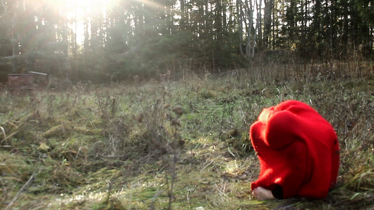  Hopkrupen person inlindad i röd filt på äng