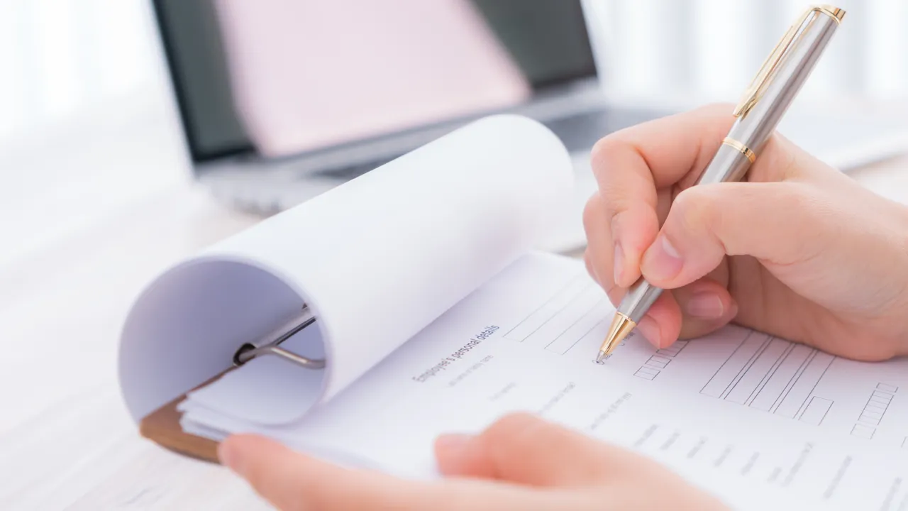 A person writing on a piece of paper with a pen