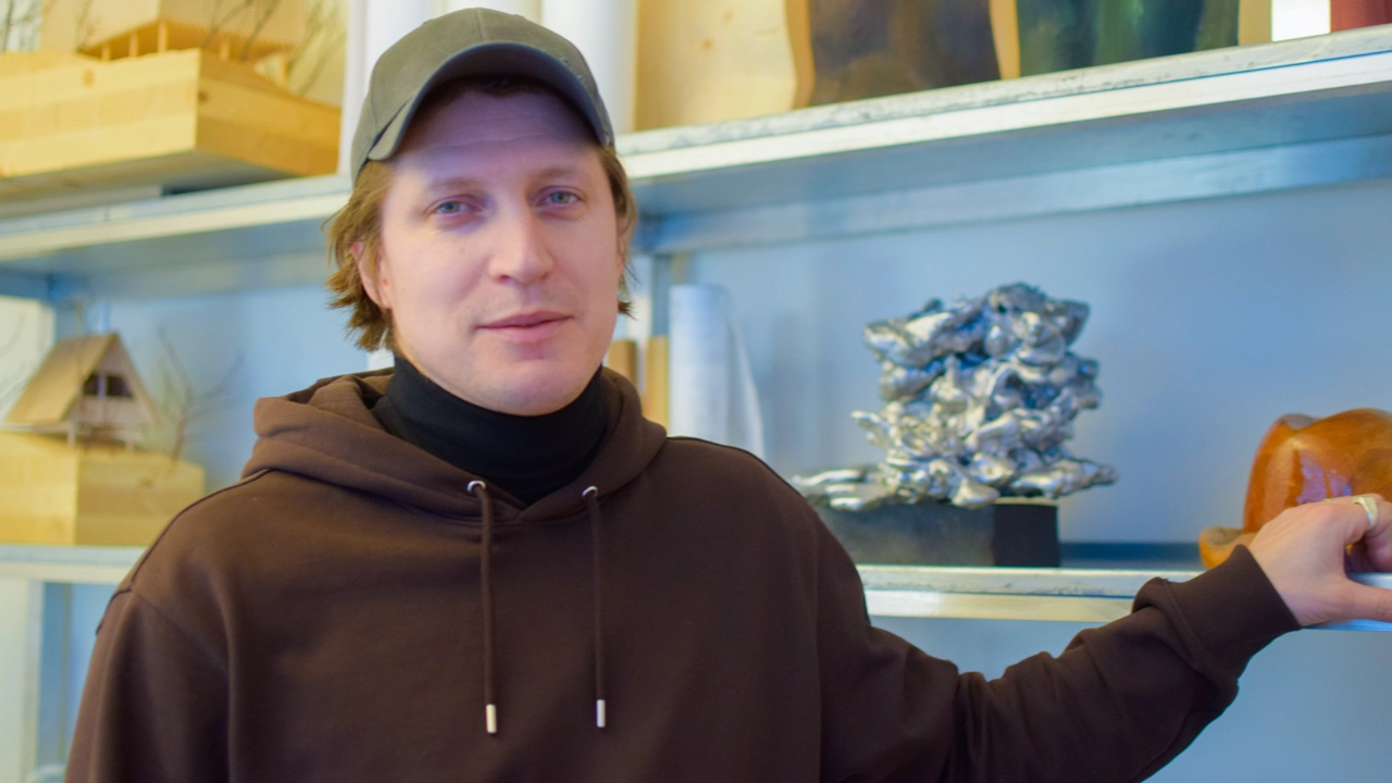 Bild på Erik Karlsson stående framför en hylla med trä- och metallföremål