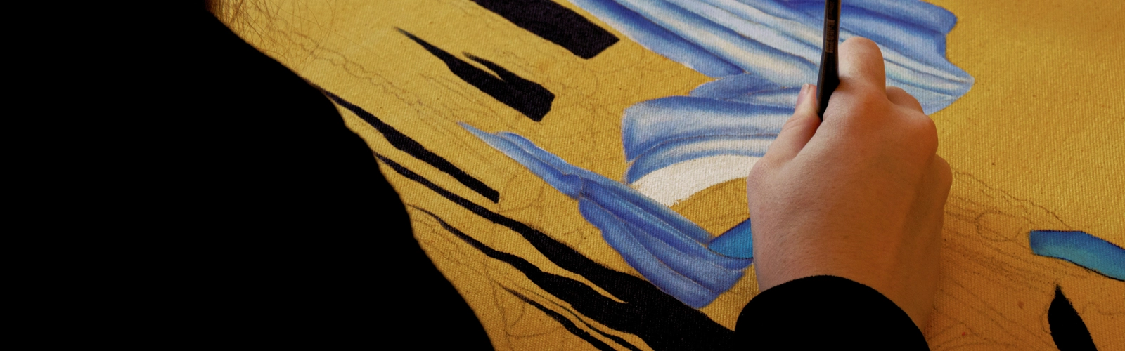 En person målar en tavla på ett bord.