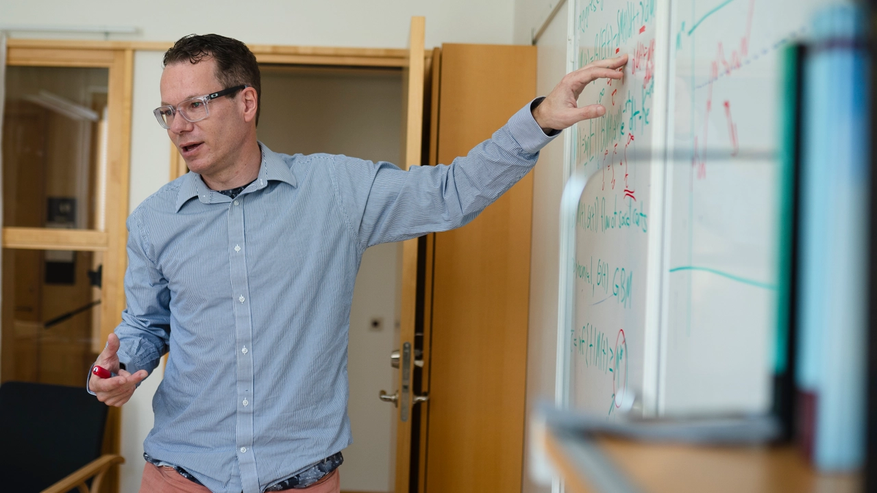 Bild på Christian Ewald, pekar på whiteboardtavla