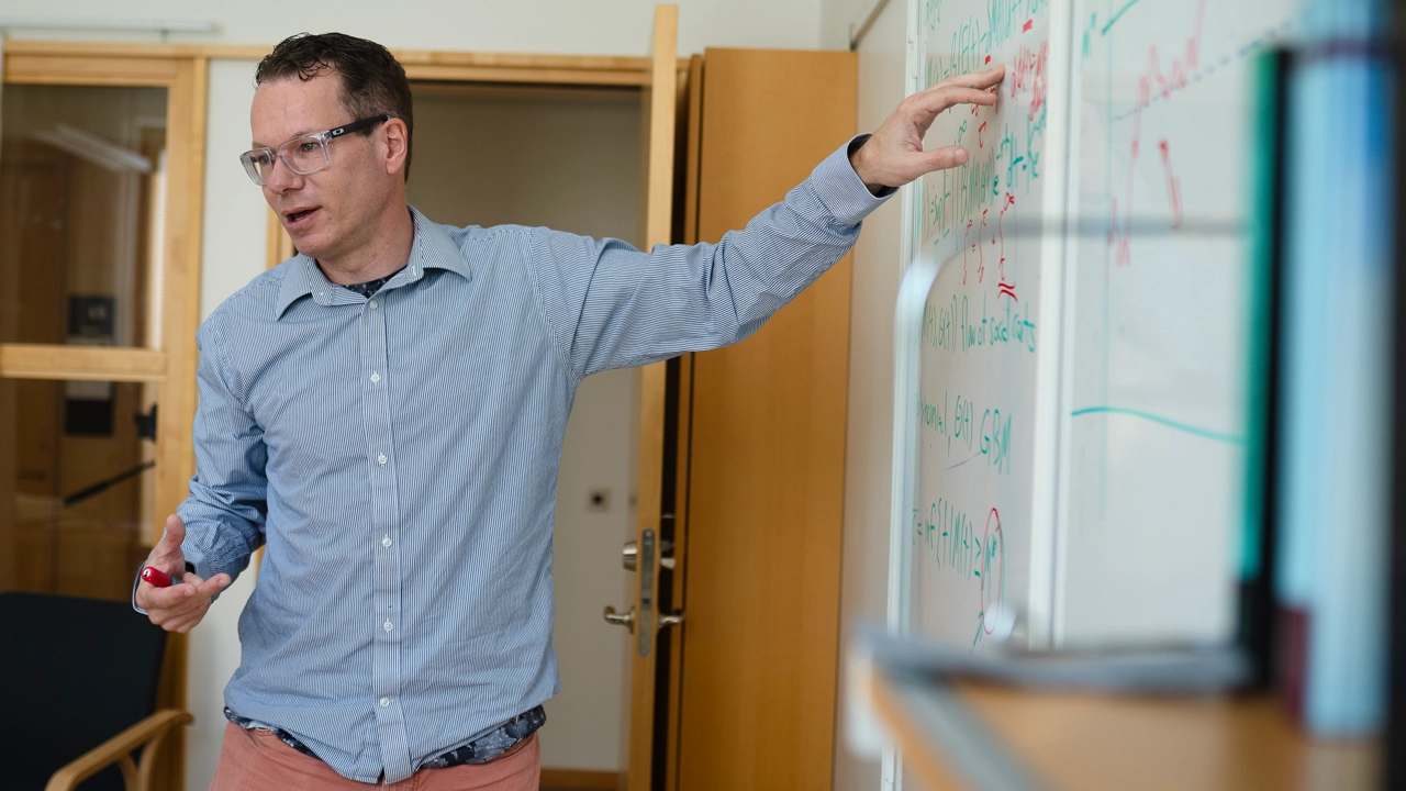 Photo of Christian Ewald, pointing to a whiteboard