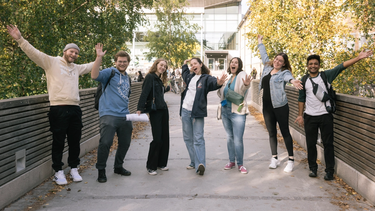 Students with hands in the air looking happy on Campus Umeå.