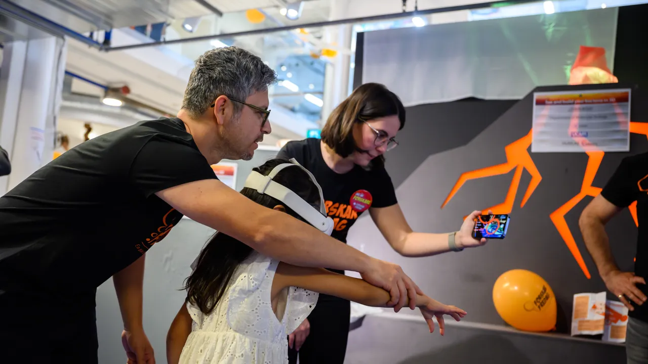A man and a woman guide a child in a white dress with a white VR headset on