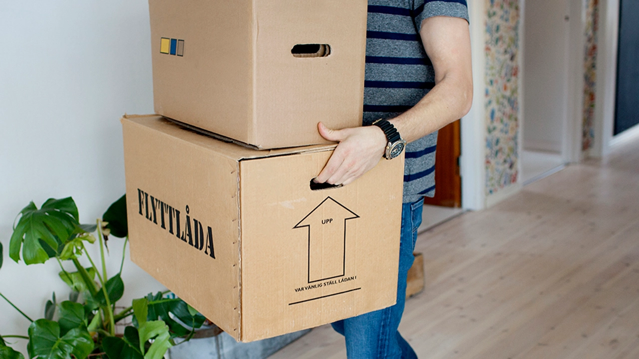 Person som bär två flyttkartonger.