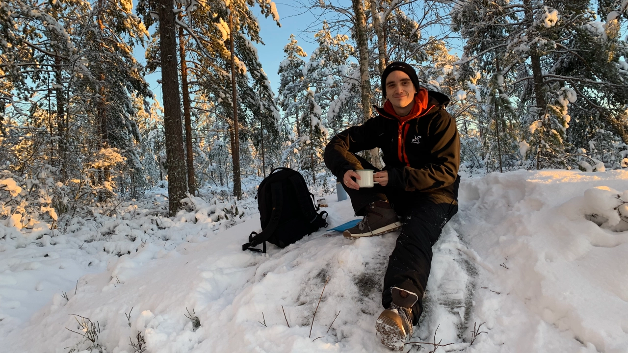 Bild på Fredrik Bredberg sittande i snödriva, snöklädda träd i bakgrunden
