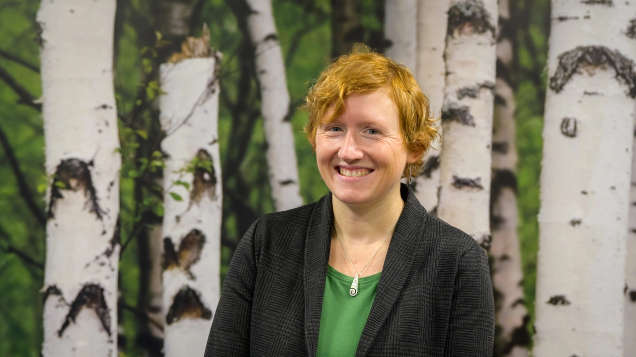 En kvinna står framför en målning med träd