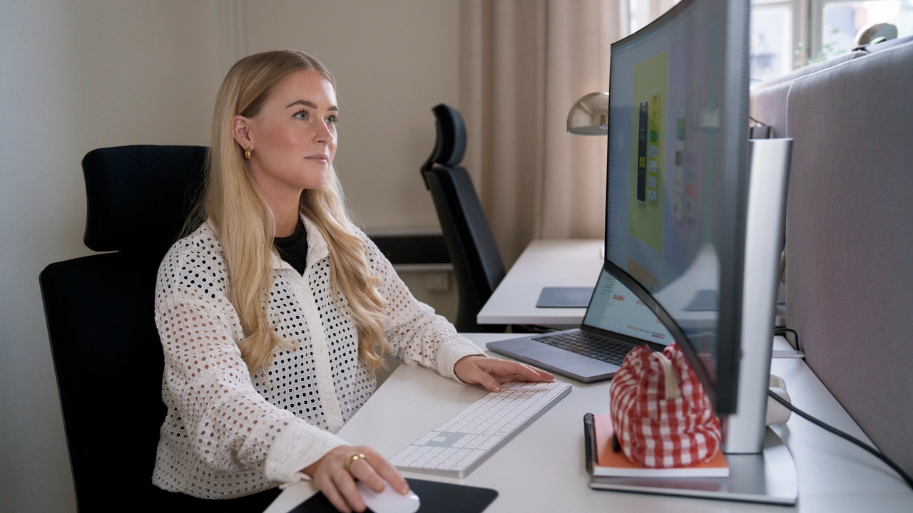 Kvinna sitter vid ett skrivbord och arbetar med datorn. 