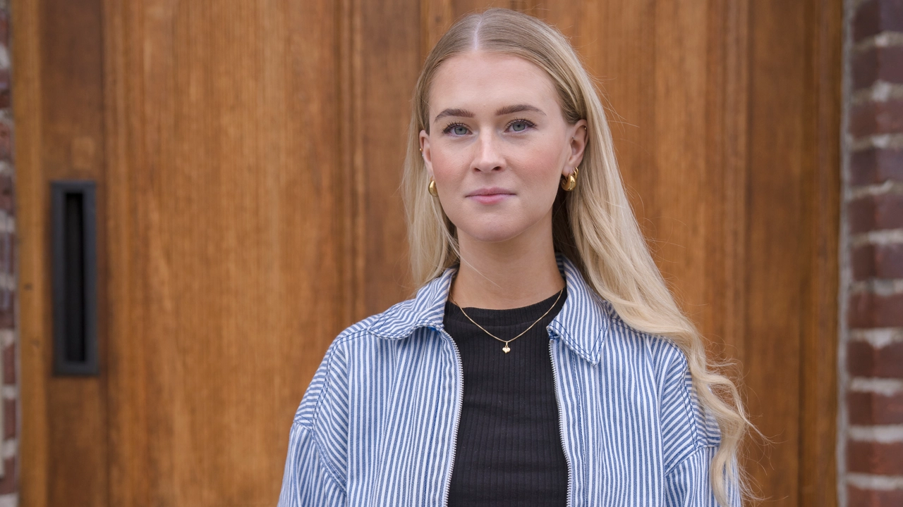 Kvinna står framför en dörr och tittar in i kameran.