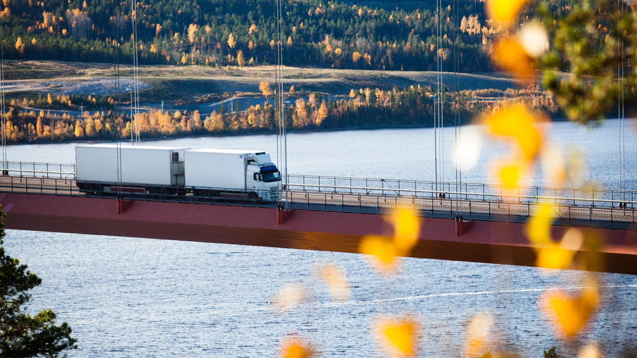 A Volvo truck crossing the High Coast Bridge in a landscape of autumnal colours.