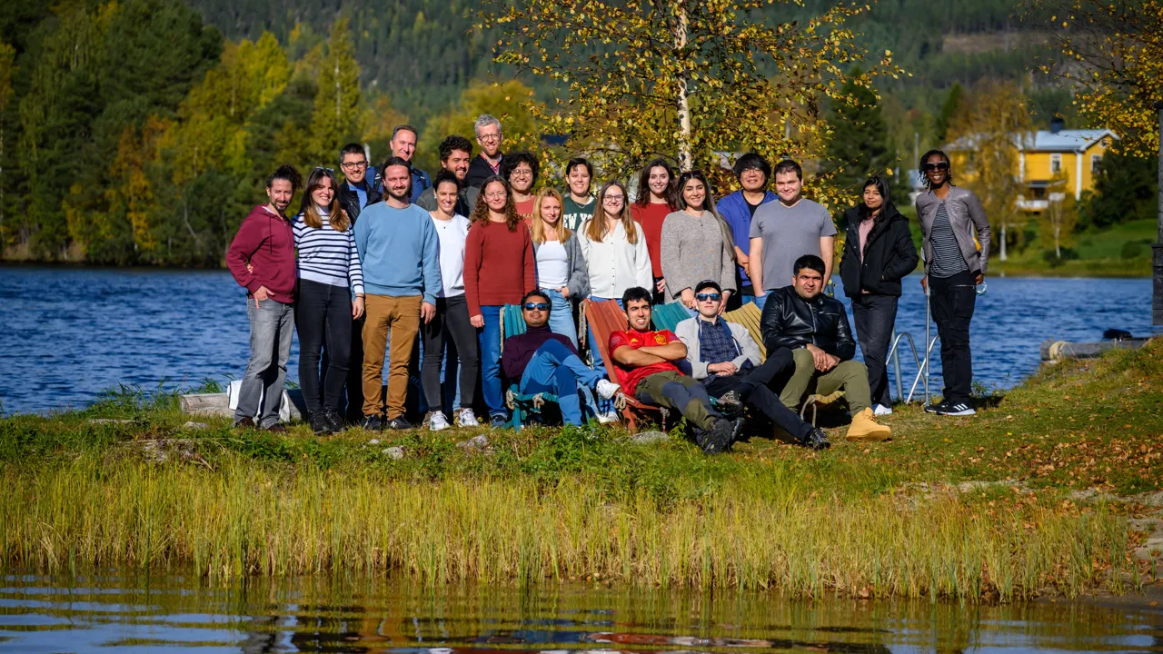 People standing in a fall landscape by a river.