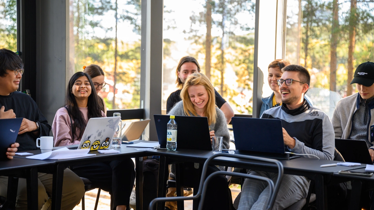 En grupp människor sitter runt ett bord med bärbara datorer