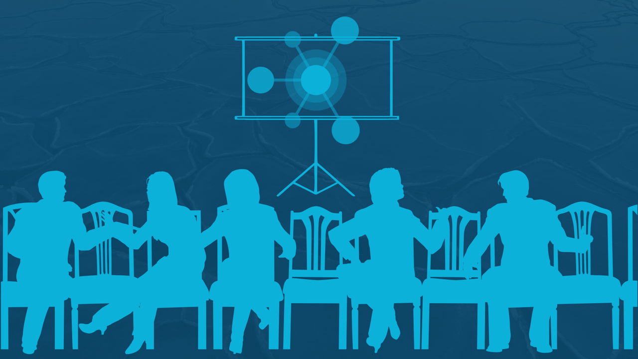 En grupp människor som sitter vid ett bord framför en projektorskärm