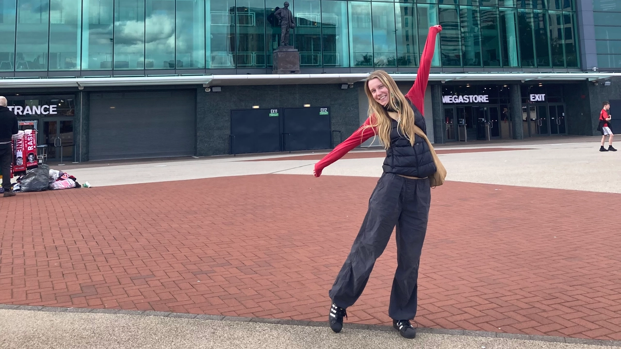 Bild på Ida Bengtsson, tar danssteg på ett torg framför ett hus med glasfasad