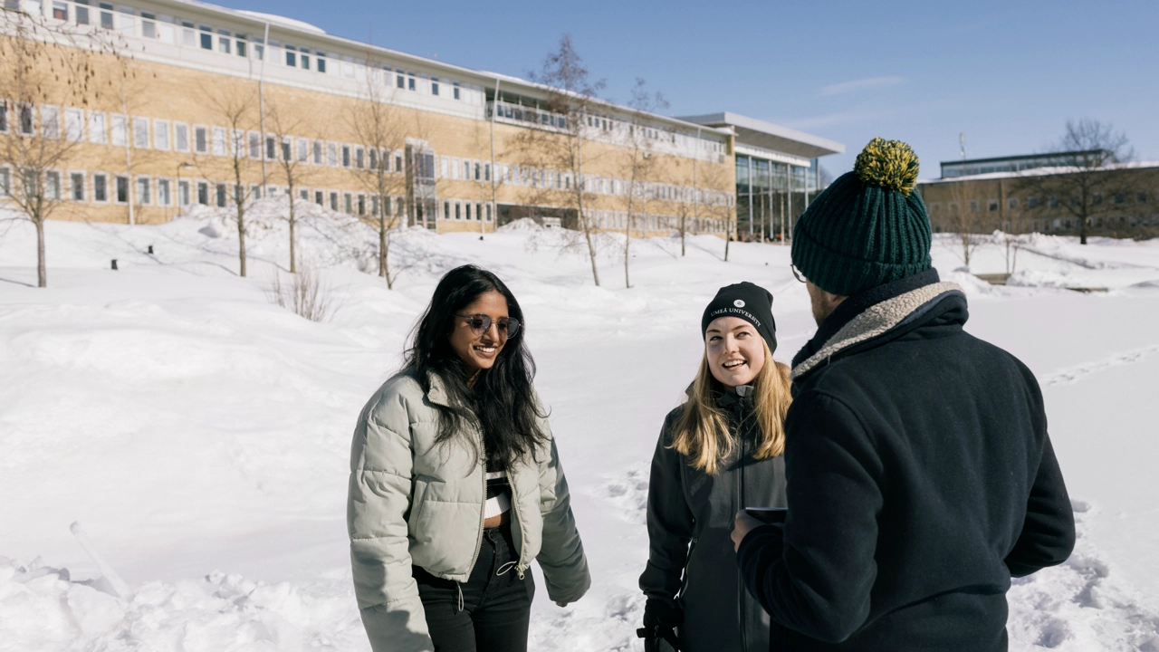 Internationella studenter vid dammen snön med Lindellhallen i bakgrunden.
