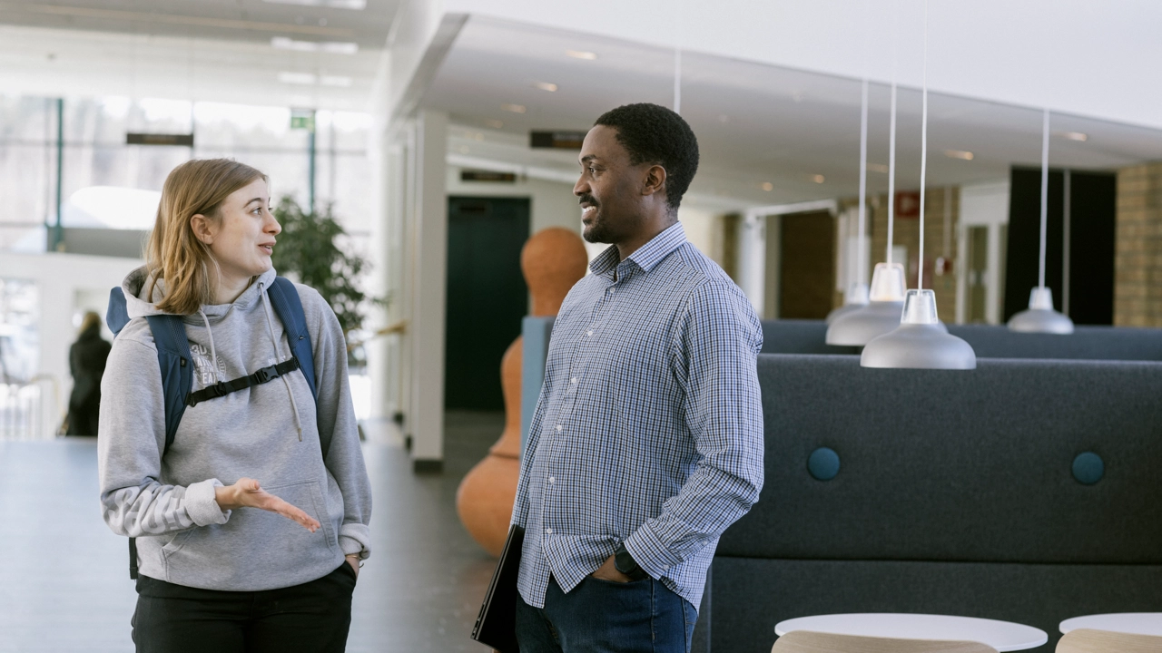 Två internationella studenter samtal i korridor i Humanisthuset.