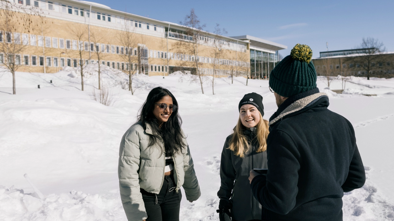 Three international students talking in a wintery landscape on Campus Umeå. 