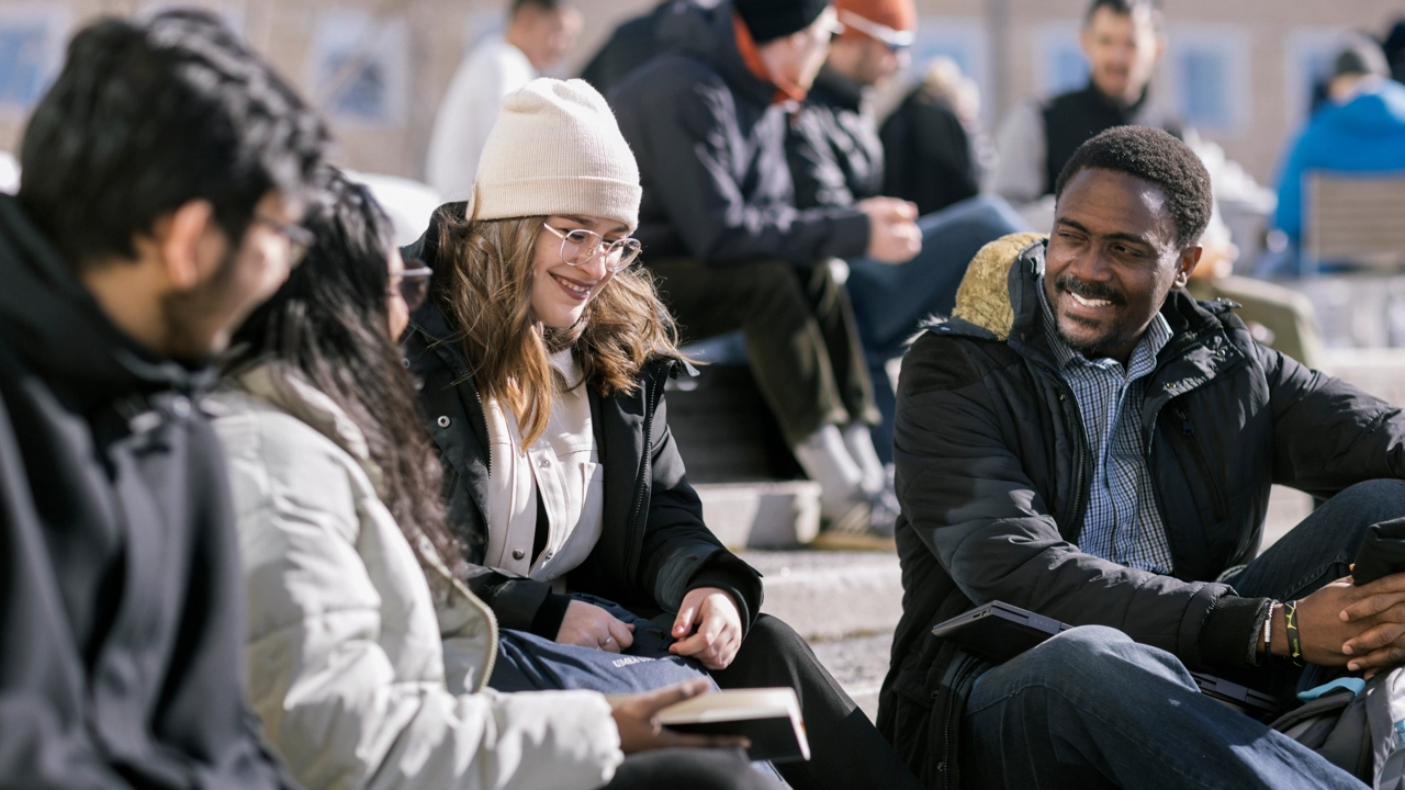 Internationella personer sitter utomhus utanför Lindellhallen.