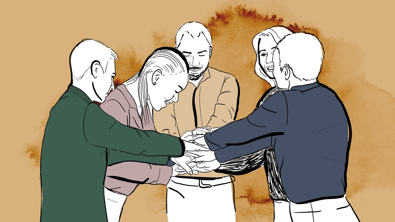 En grupp personer står i en ring med händerna tillsammans i mitten.