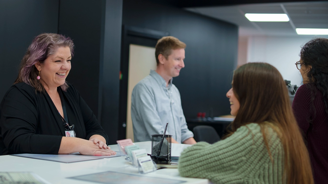 Staff welcoming new students and providing support at the infocenter service desk.