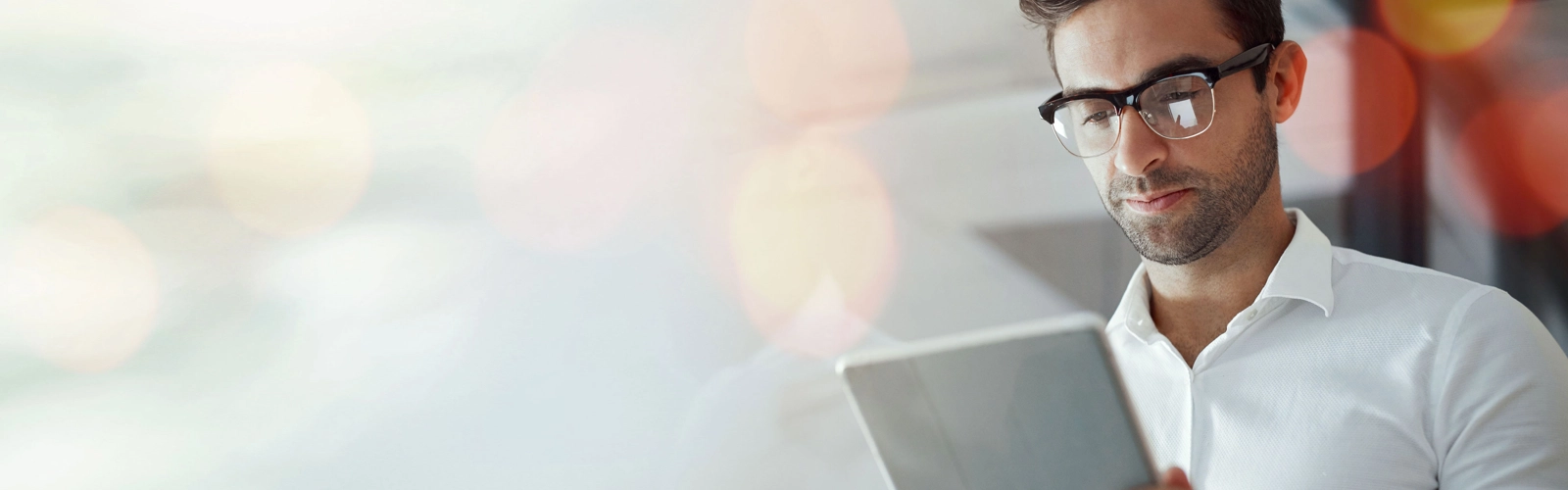 En man med glasögon tittar på en surfplatta.