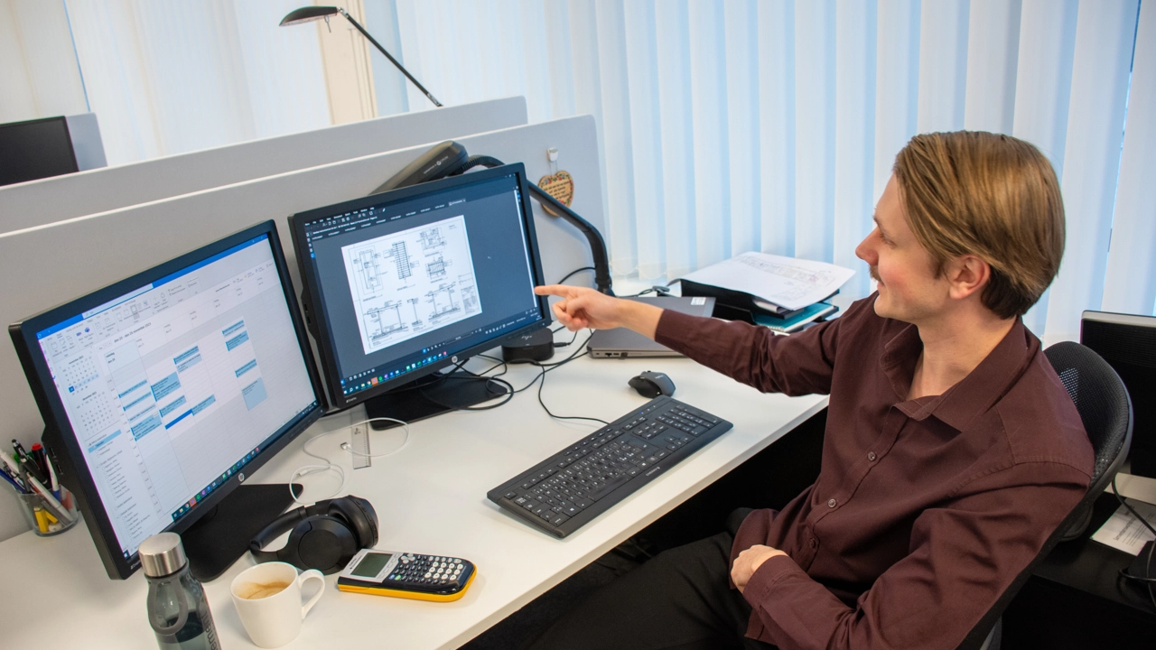 Bild på Jesper Lagerström sittande vid skrivbord med två datorskärmar