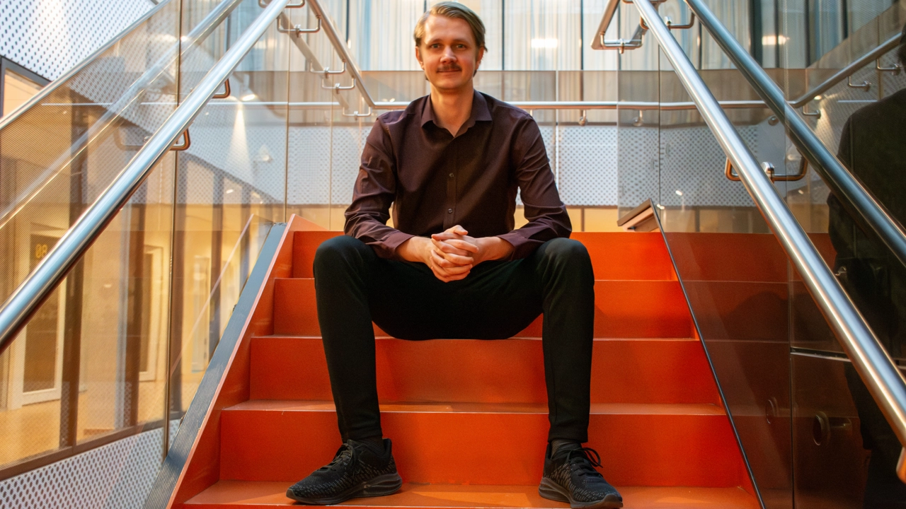 Bild på Jesper Lagerström sittande i en trappa med rött golv