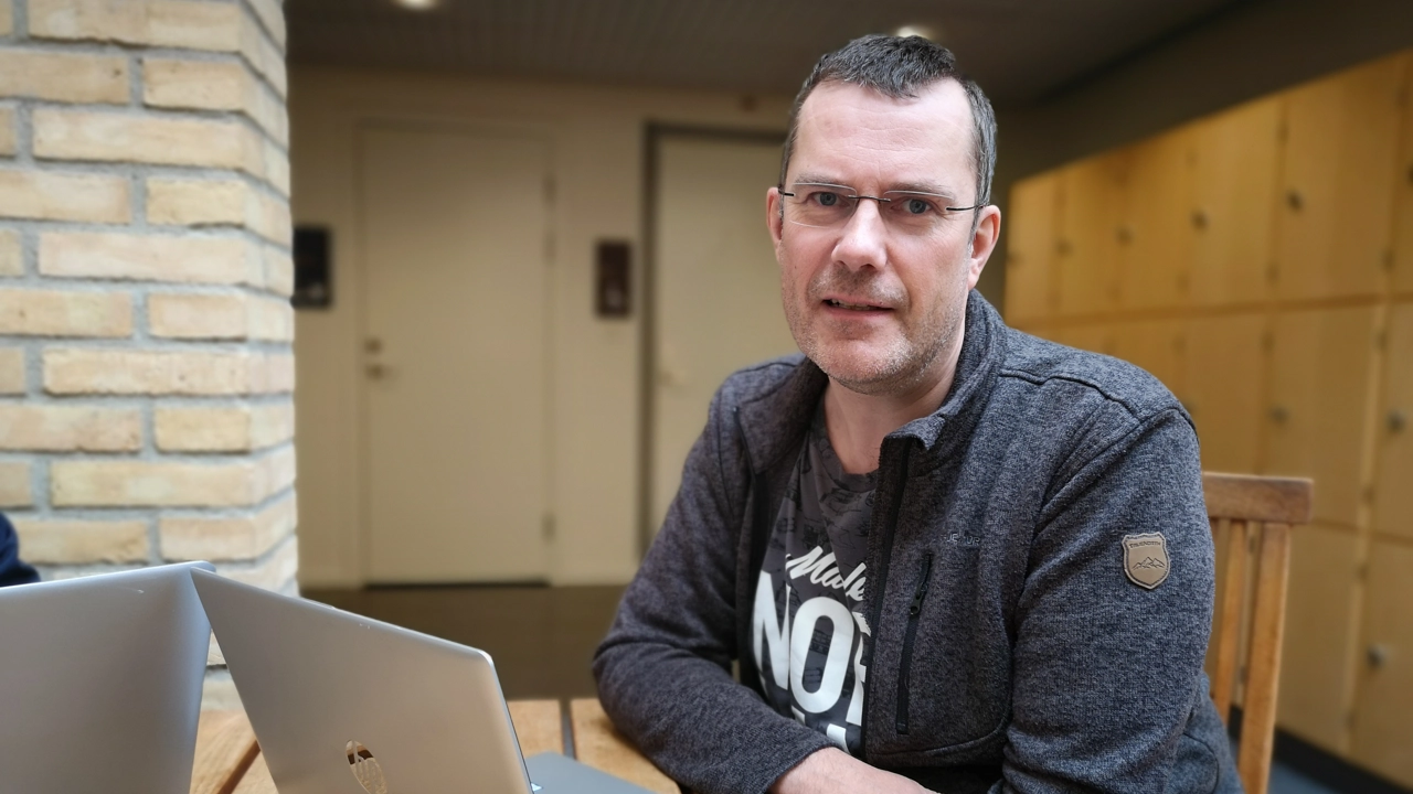 En man som sitter vid ett bord vid en dator