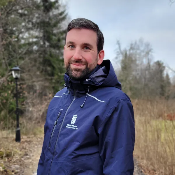 Joel Avenius stående med skogsmark i bakgrunden