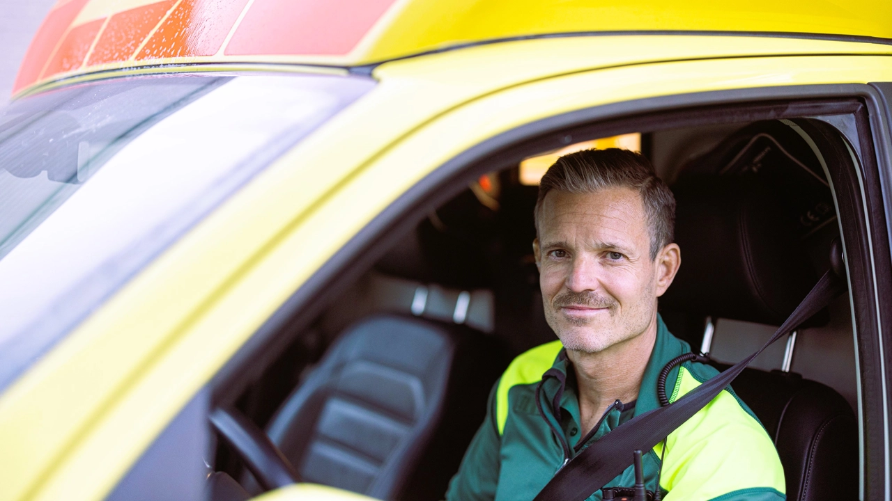Ambulansförare sitter i ambulans. 