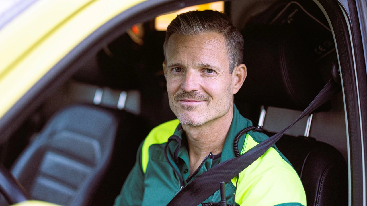 En manlig ambulansförare sitter i en ambulansbil.