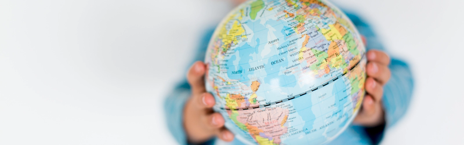 Barn håller upp en liten jordglob mellan sina händer.