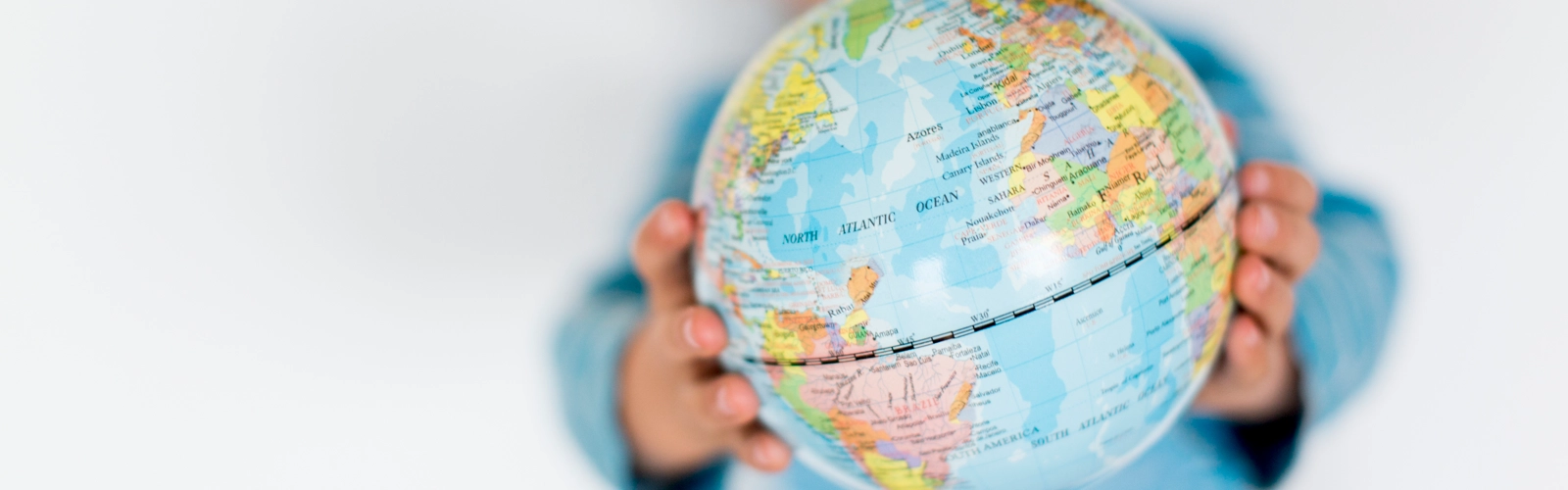 Barn håller upp en liten jordglob mellan sina händer.