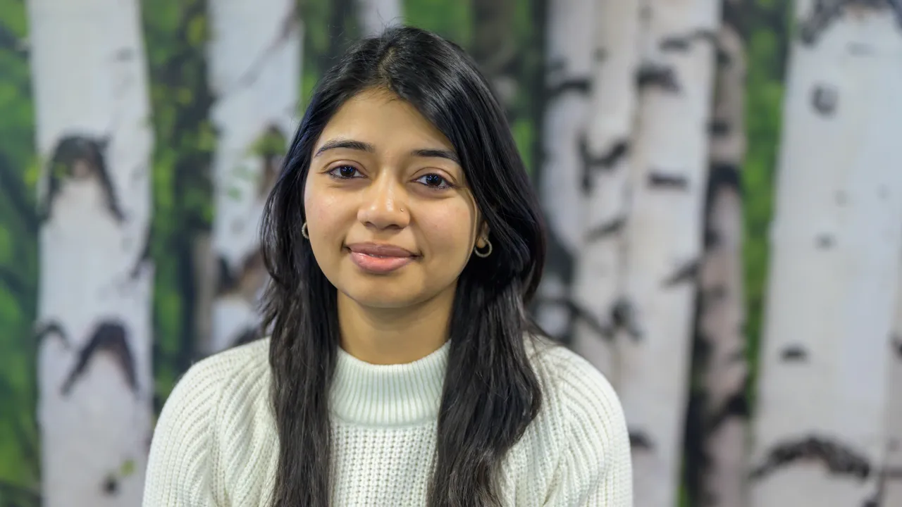 A woman standing in front of a painting of birch trees